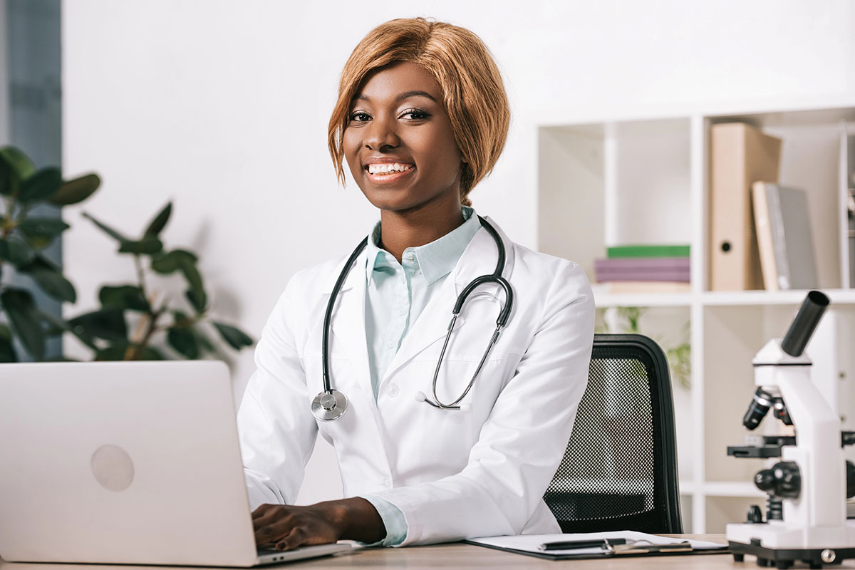 Smiling doctor using a laptop, representing Albuquerque healthcare IT.