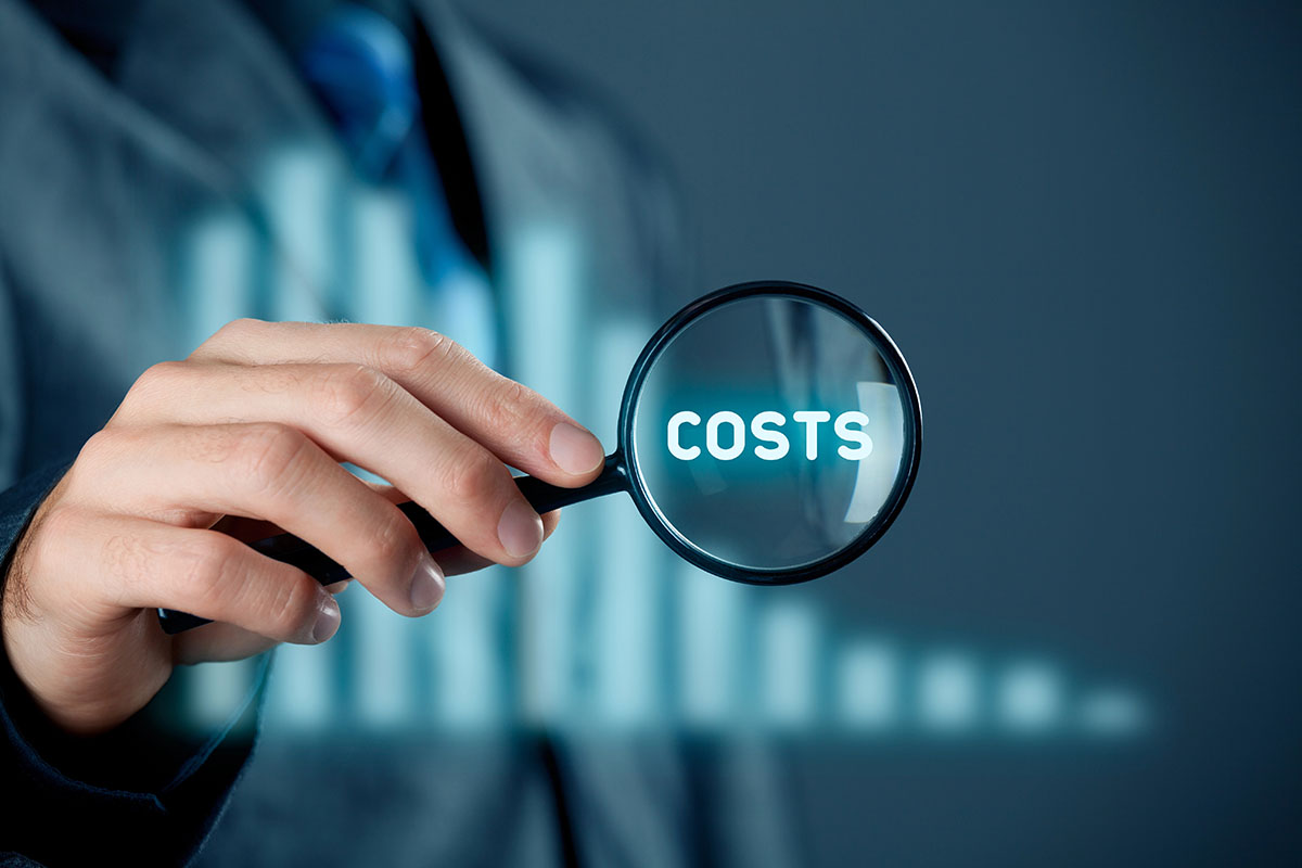 A person in a suit holds a magnifying glass over the word "COSTS," surrounded by a blurred background suggesting a business context.